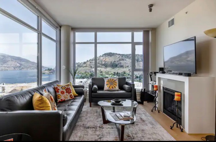 Living room with 2 large windows, Couch, Love Seat, Flat Screen TV, fireplace, and a glass top coffee table