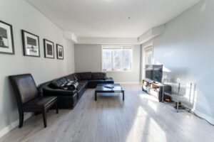 Room with a chair, couch, coffee table, TV, and Large Window